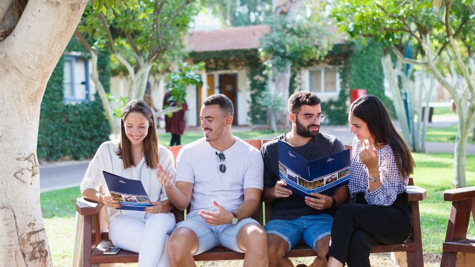 Picture of people sitting on a bench reading brochures